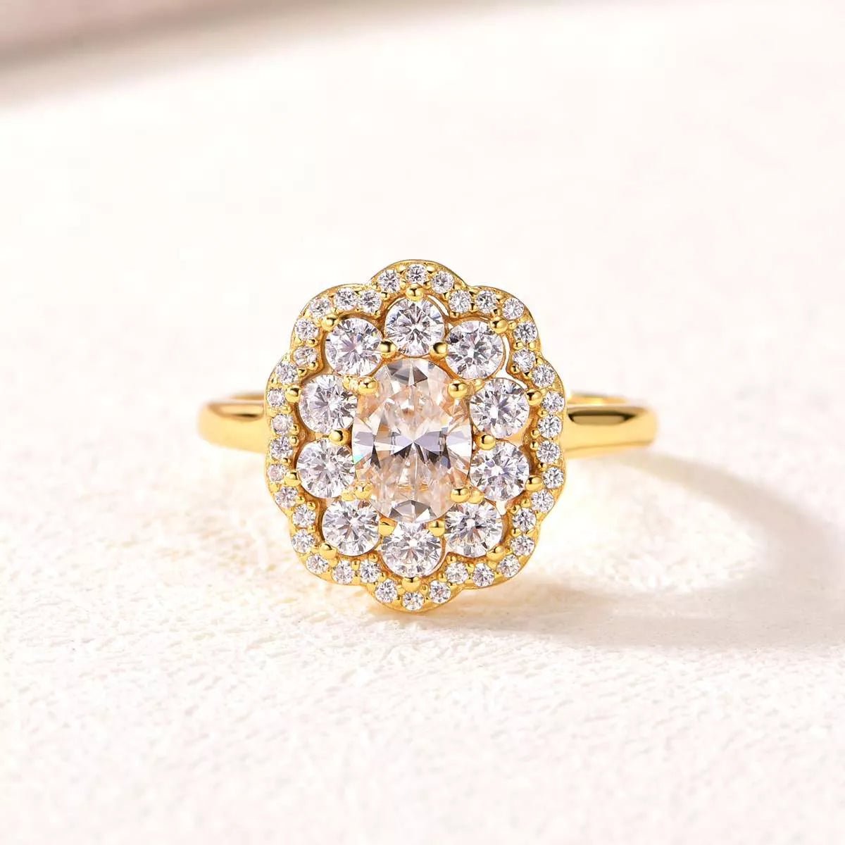 Gold ring with a large central diamond and smaller diamonds around on a light background