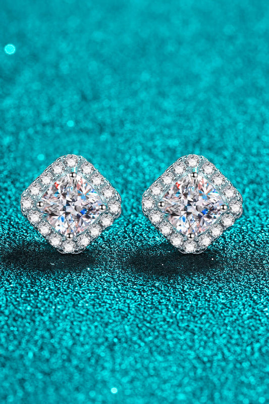 Pair of diamond stud earrings on a teal glitter background