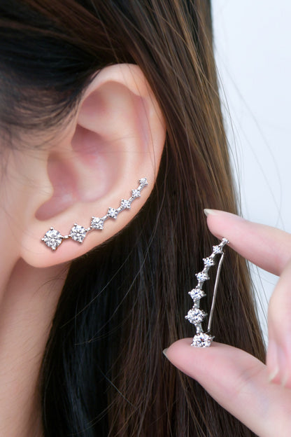 Silver ear cuff being worn on an ear with a hand holding another identical ear cuff.