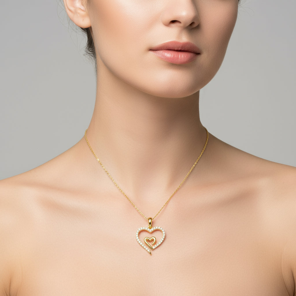 Gold necklace with a heart-shaped pendant worn by a model against a neutral background
