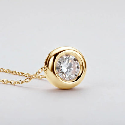 Gold necklace with a diamond pendant on a light gray background