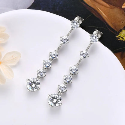 Silver earrings with clear stones on a white plate with a blurred background