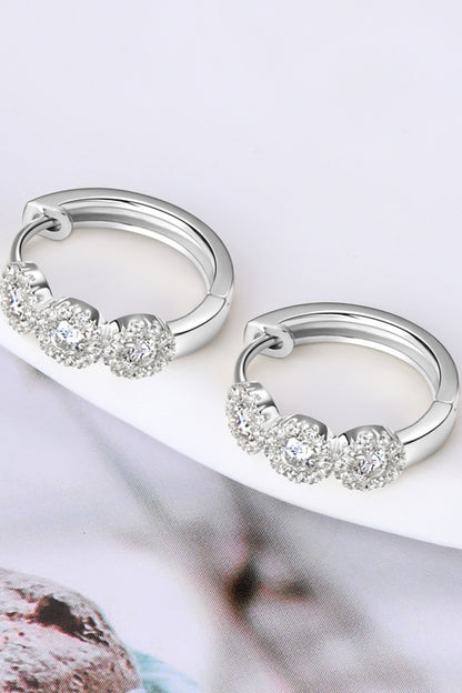 Silver hoop earrings with clear gemstones on a white surface.