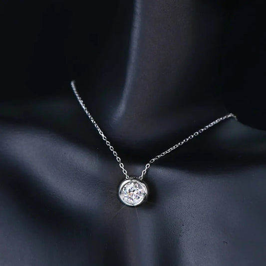 Silver necklace with a round pendant on a dark fabric background