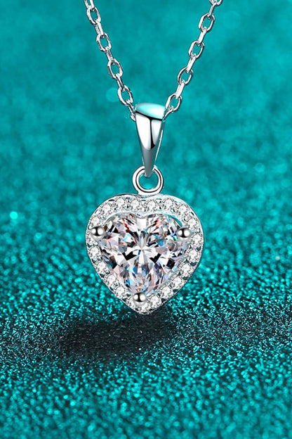Heart-shaped diamond pendant on a chain against a teal background