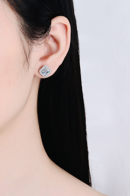 Close-up of a person wearing a diamond stud earring on a plain background
