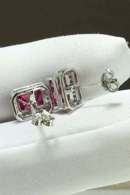 Silver earrings with pink gemstones on a white cushion