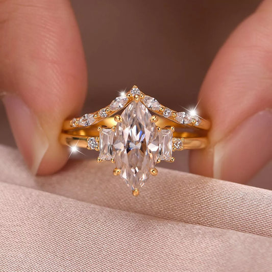 Gold ring with a large diamond held between fingers on a soft fabric background