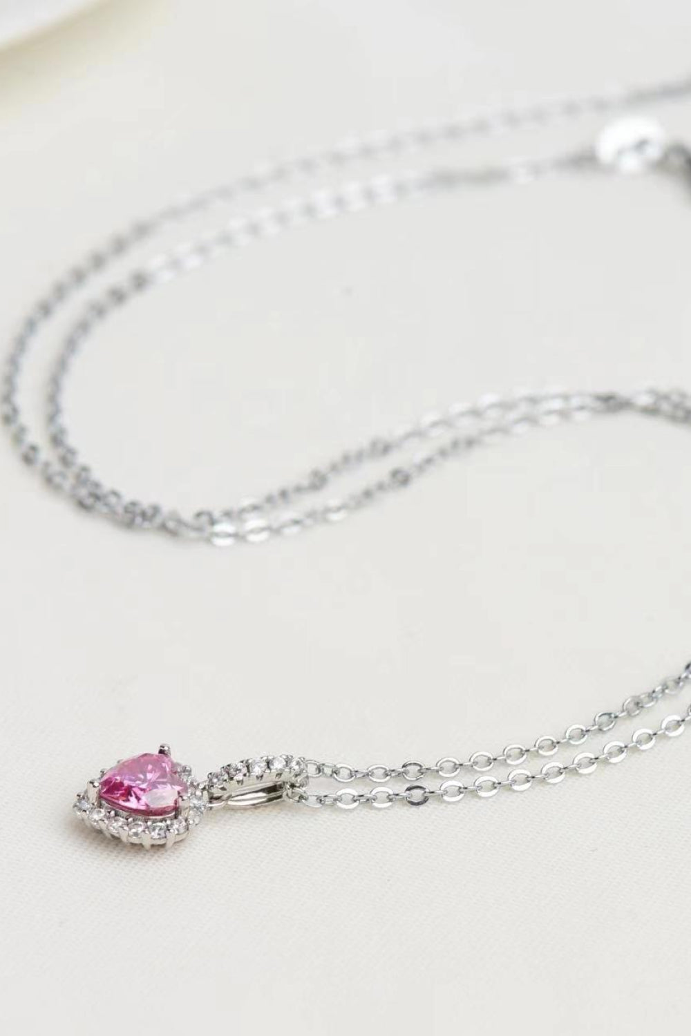 Silver necklace with a pink gemstone pendant on a light background