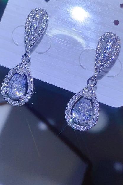 Teardrop-shaped earrings with clear gemstones on a reflective surface