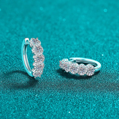 Silver hoop earrings with clear gemstones on a teal background