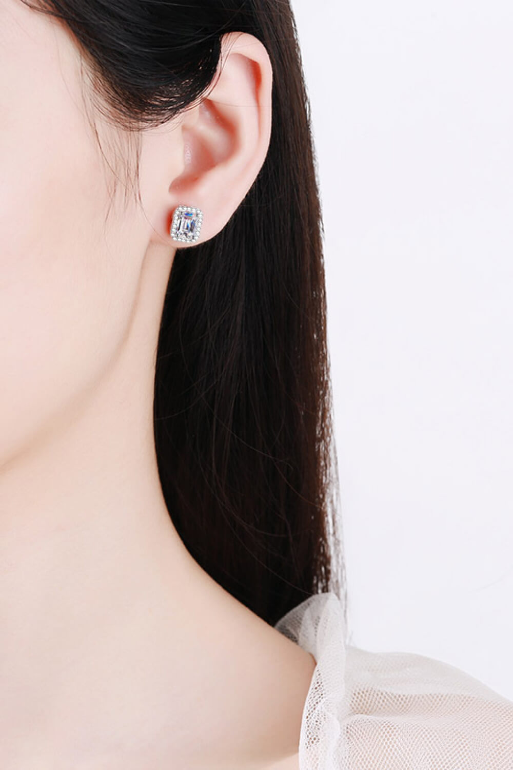 Close-up of a person wearing a silver earring with a blue gemstone on a white background
