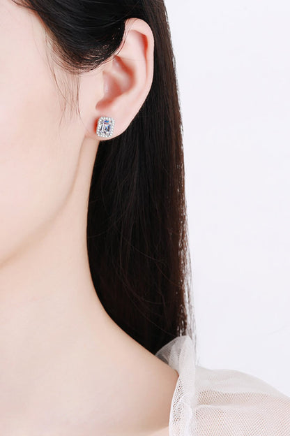 Close-up of a person wearing a silver earring with a blue gemstone on a white background