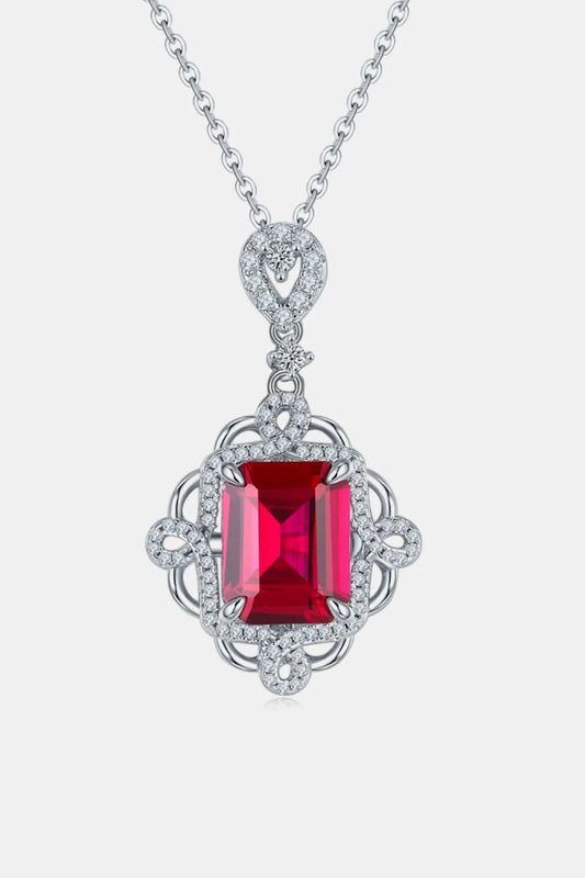 Elegant silver necklace with a red gemstone pendant on a white background