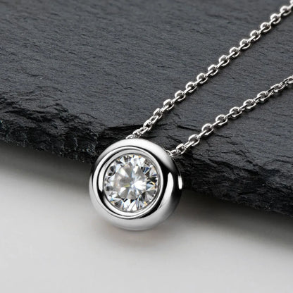 Silver necklace with a diamond pendant on a dark stone surface