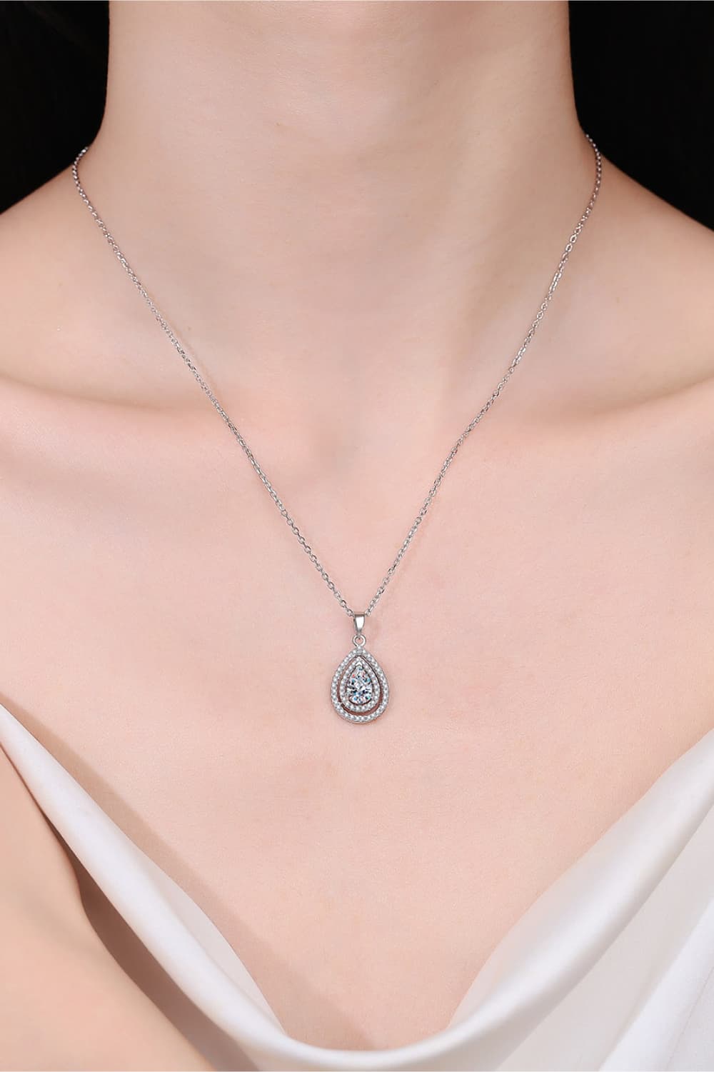 Silver teardrop necklace on a model with a plain background