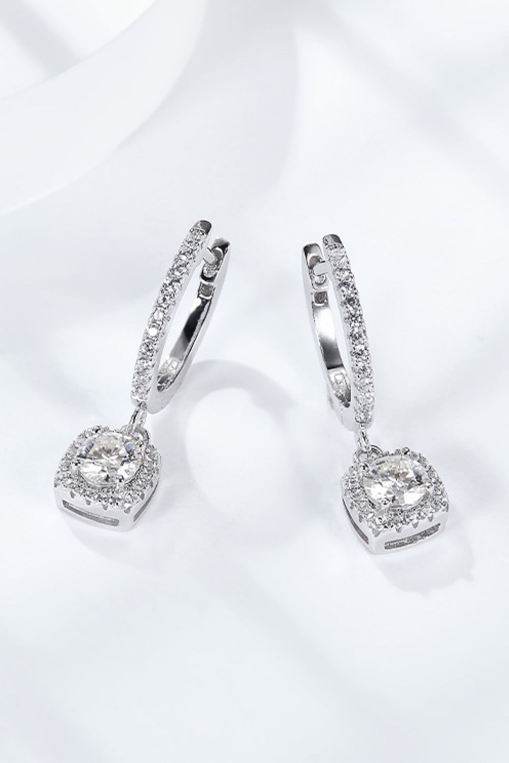 Pair of silver hoop earrings with clear gemstones on a white background