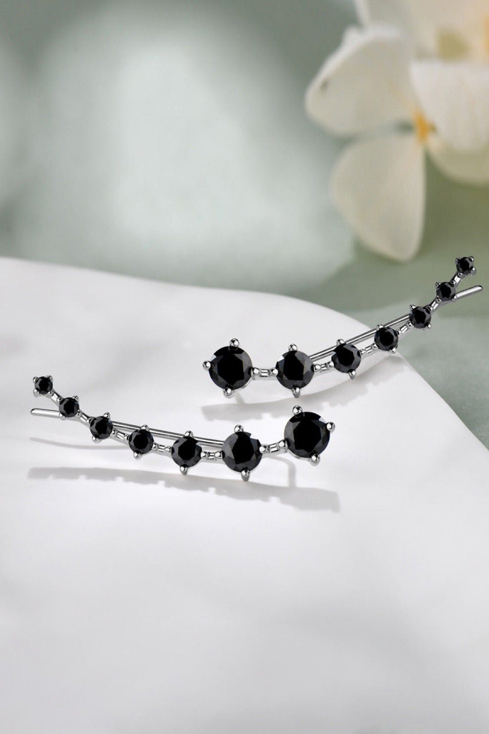 Silver hairpin with black gemstones on a white surface with a blurred background
