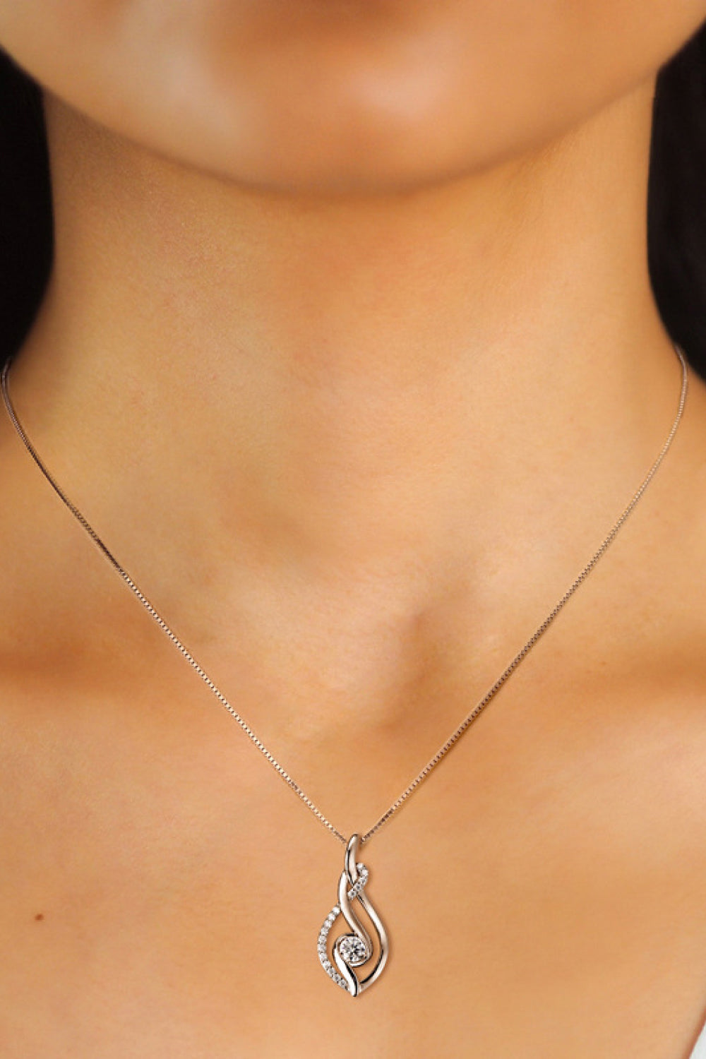 Silver necklace with a heart-shaped pendant on a person's neck