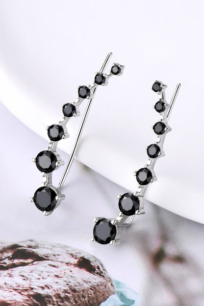 Black gemstone earrings on a white surface with a blurred background