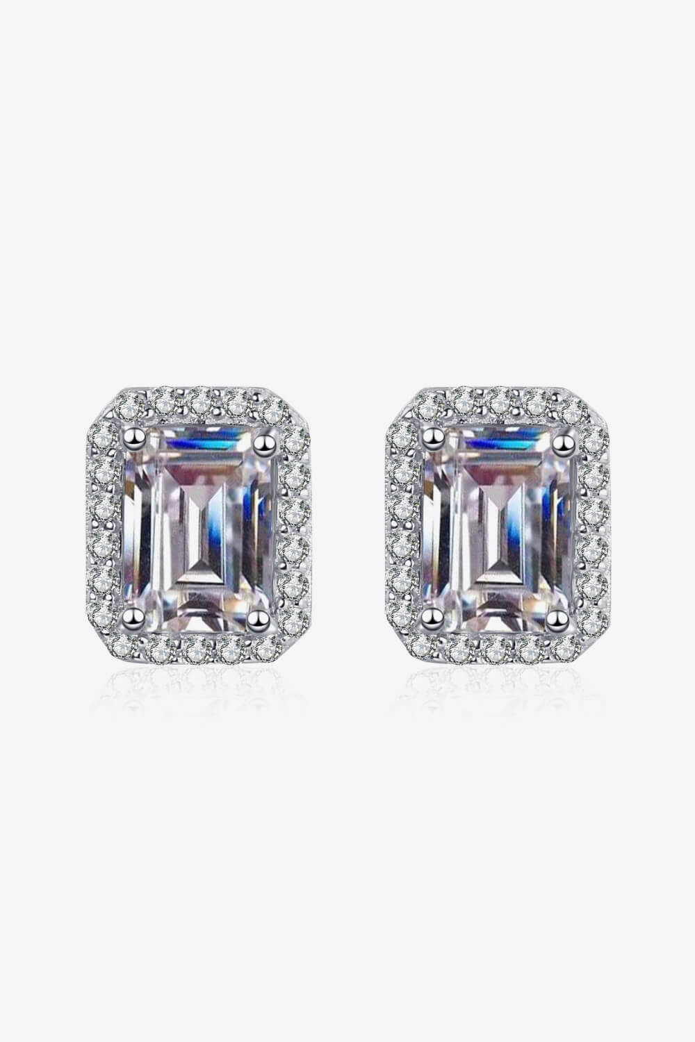 Pair of emerald-cut gemstone earrings with silver surround on a white background