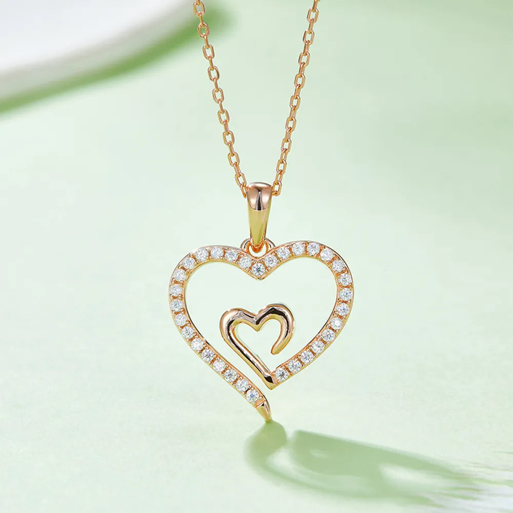 Gold heart-shaped necklace with embedded stones on a light green background