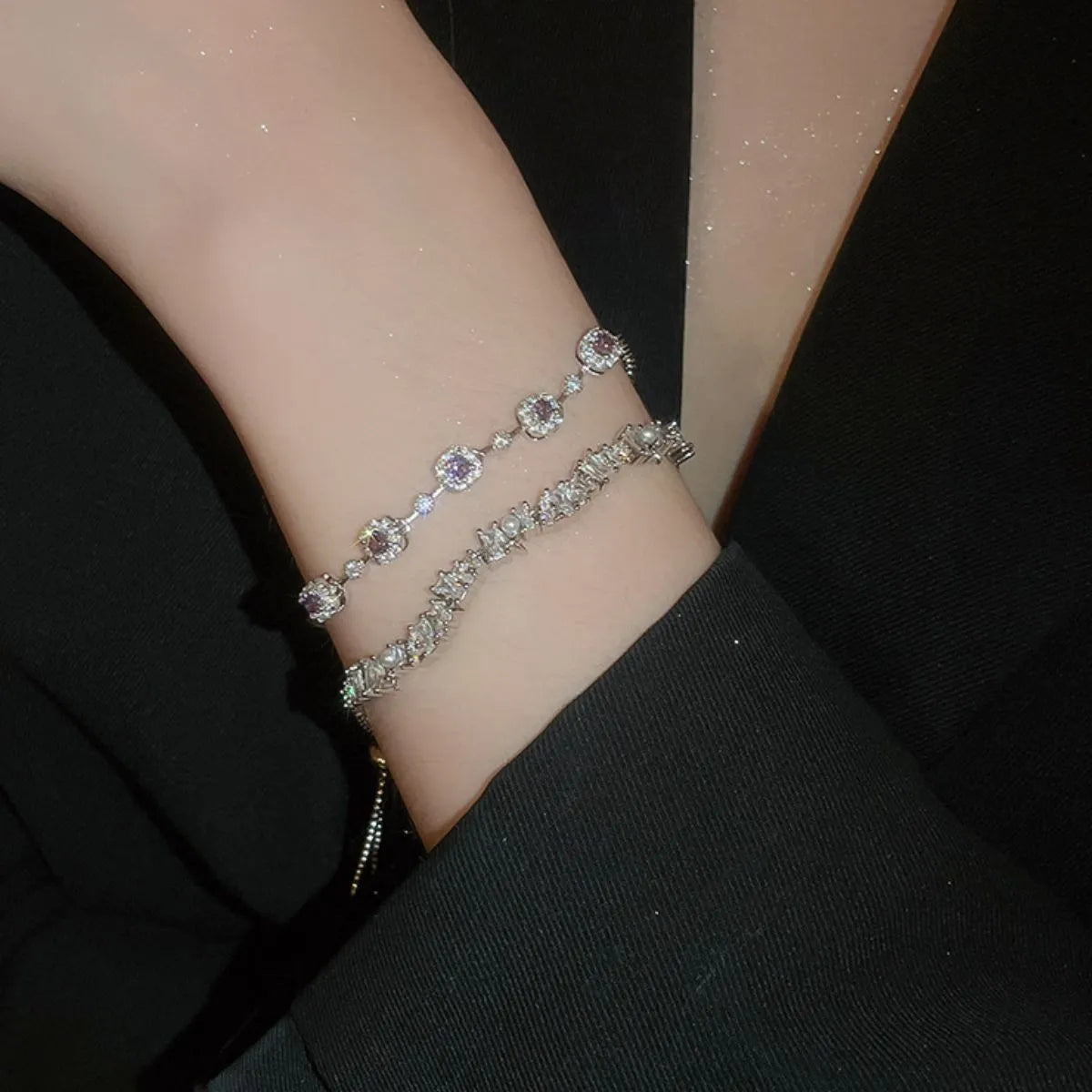 Silver bracelet with gemstones on a wrist against a dark background