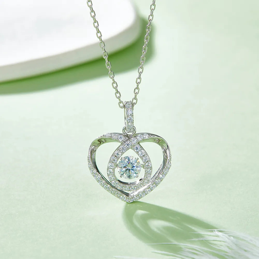 Heart-shaped silver pendant with a central gemstone on a light green background