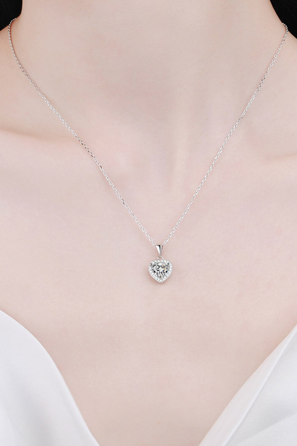 Heart-shaped silver pendant necklace on a mannequin with a plain background