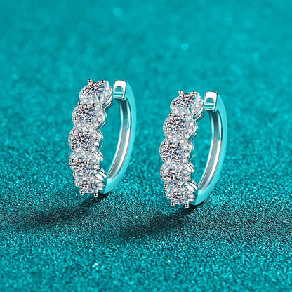 Silver hoop earrings with clear gemstones on a teal background