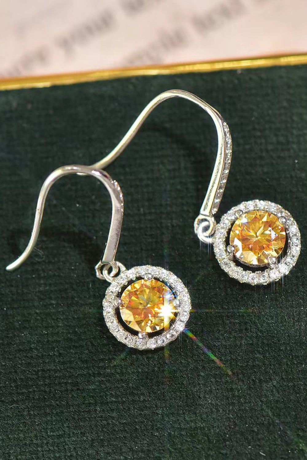 Silver earrings with yellow gemstones on a green surface