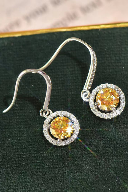 Silver earrings with yellow gemstones on a green surface