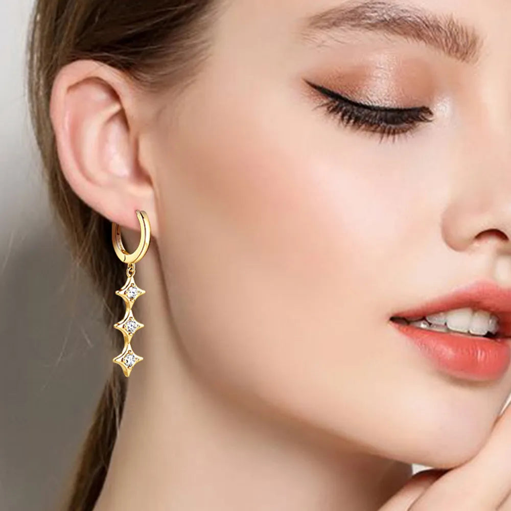Close-up of a woman wearing gold earrings with star designs.