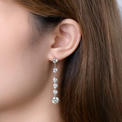 Close-up of a woman wearing a diamond earring with a neutral background