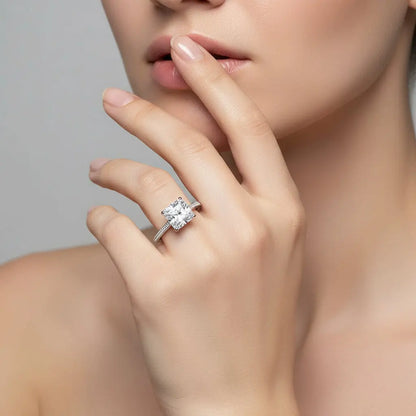 Close-up of a hand wearing a diamond ring on a neutral background