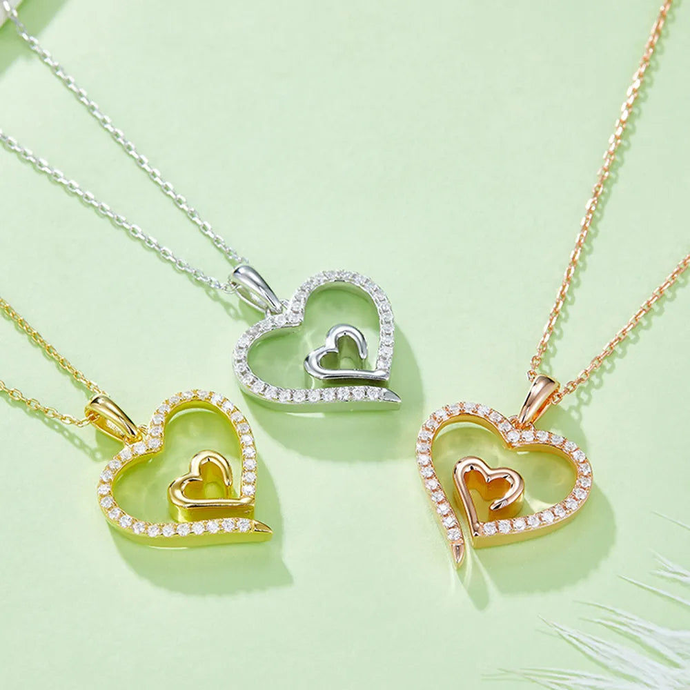 Heart-shaped pendants in gold, silver, and rose gold on a light green background
