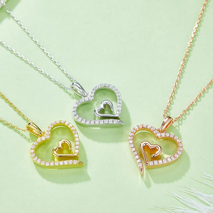 Heart-shaped pendants in gold, silver, and rose gold on a light green background