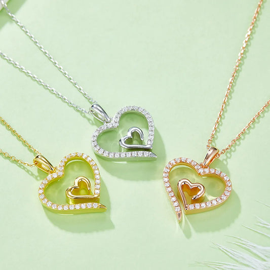 Heart-shaped pendants in gold, silver, and rose gold on a light green background