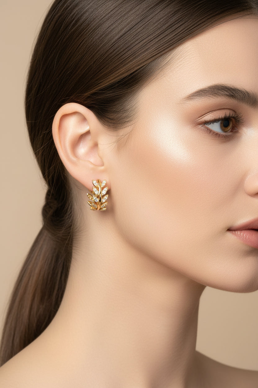 Close-up of a woman wearing gold earrings with a neutral background