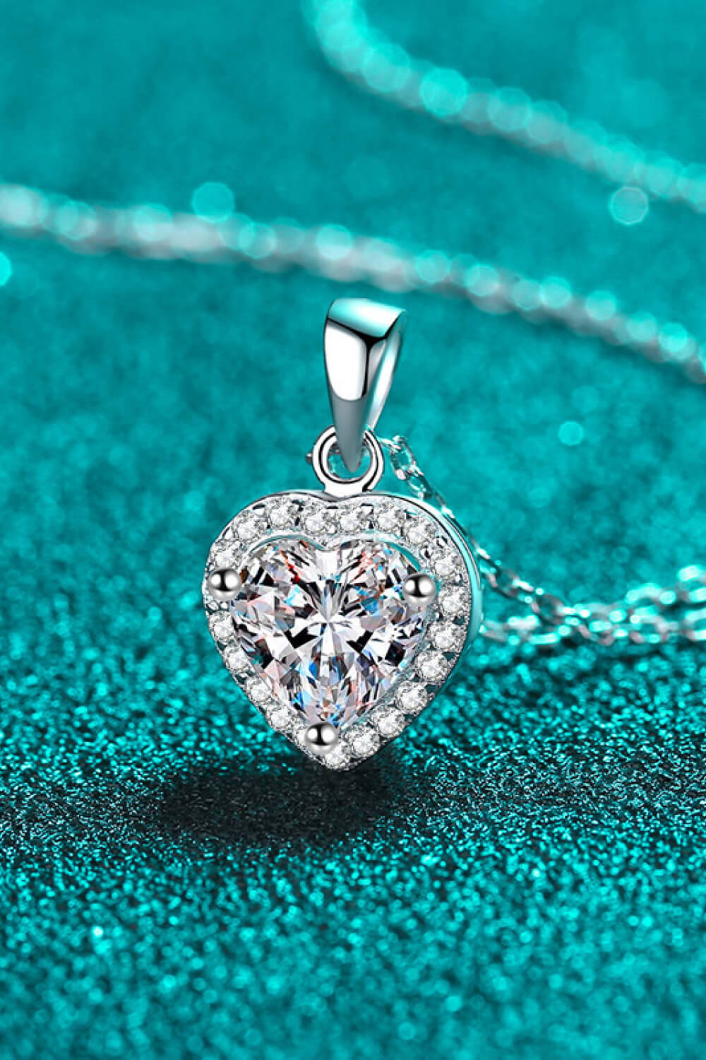 Heart-shaped diamond pendant on a turquoise background