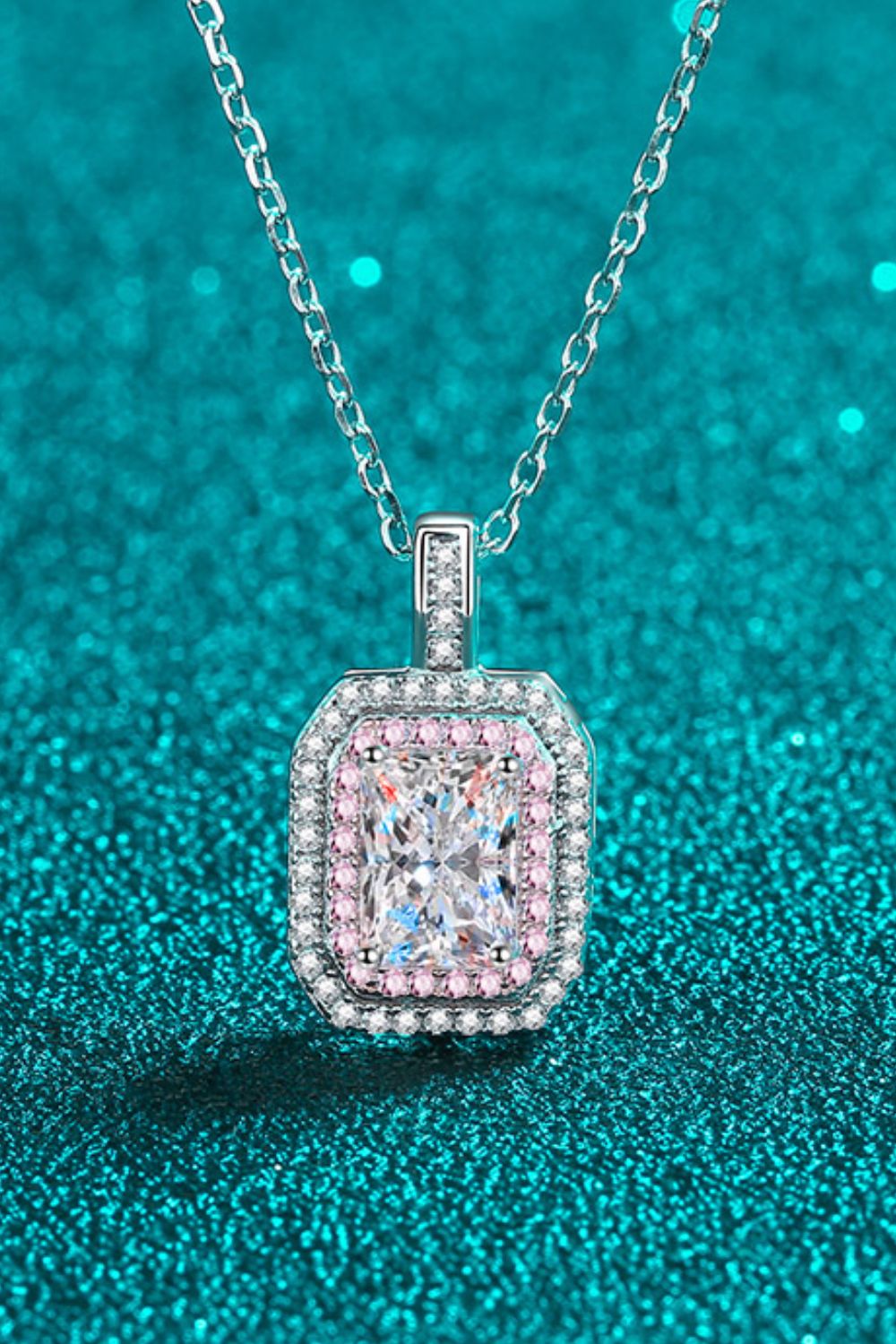Diamond pendant necklace on a teal glittery background