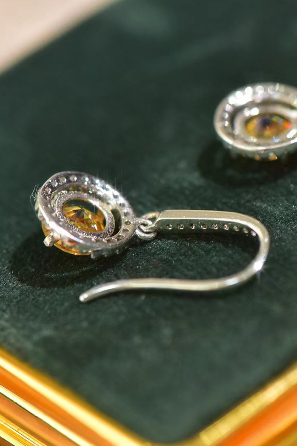 Silver earrings with orange gemstones on a green surface