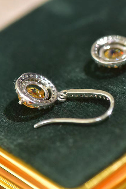 Silver earrings with orange gemstones on a green surface